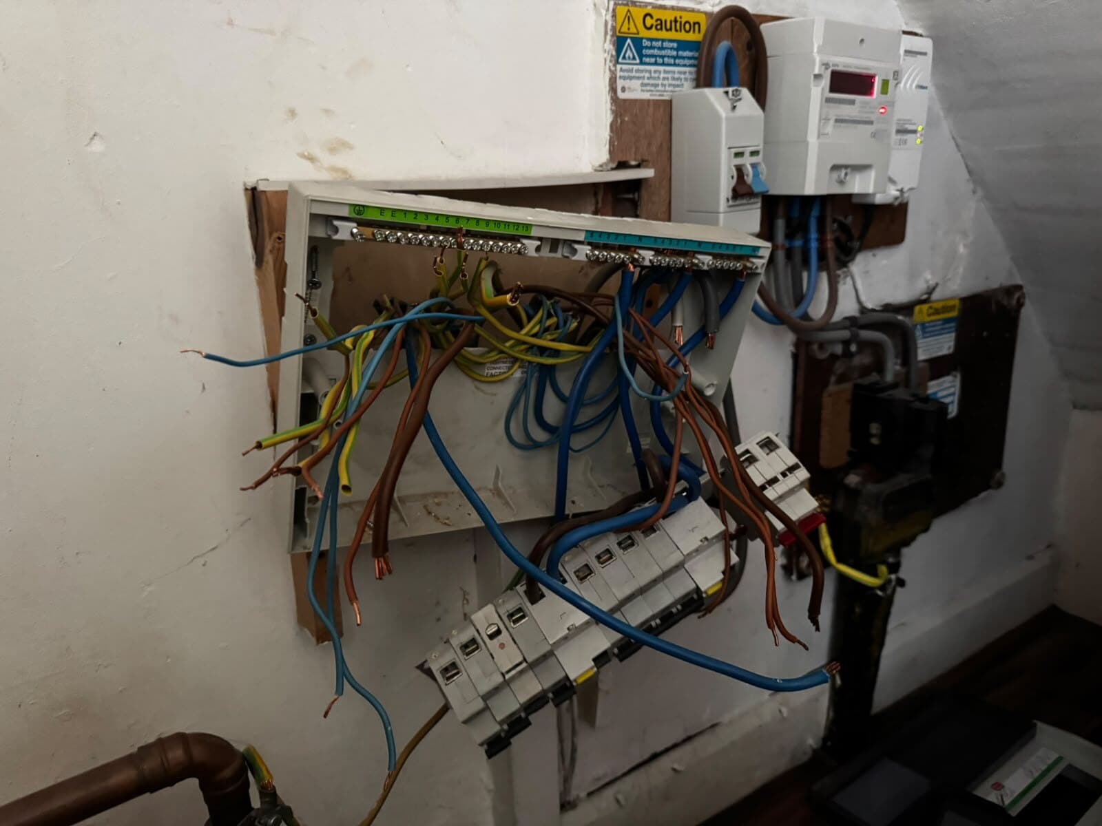Old fuse box stripped out and the new consumer unit being wired in at the meter