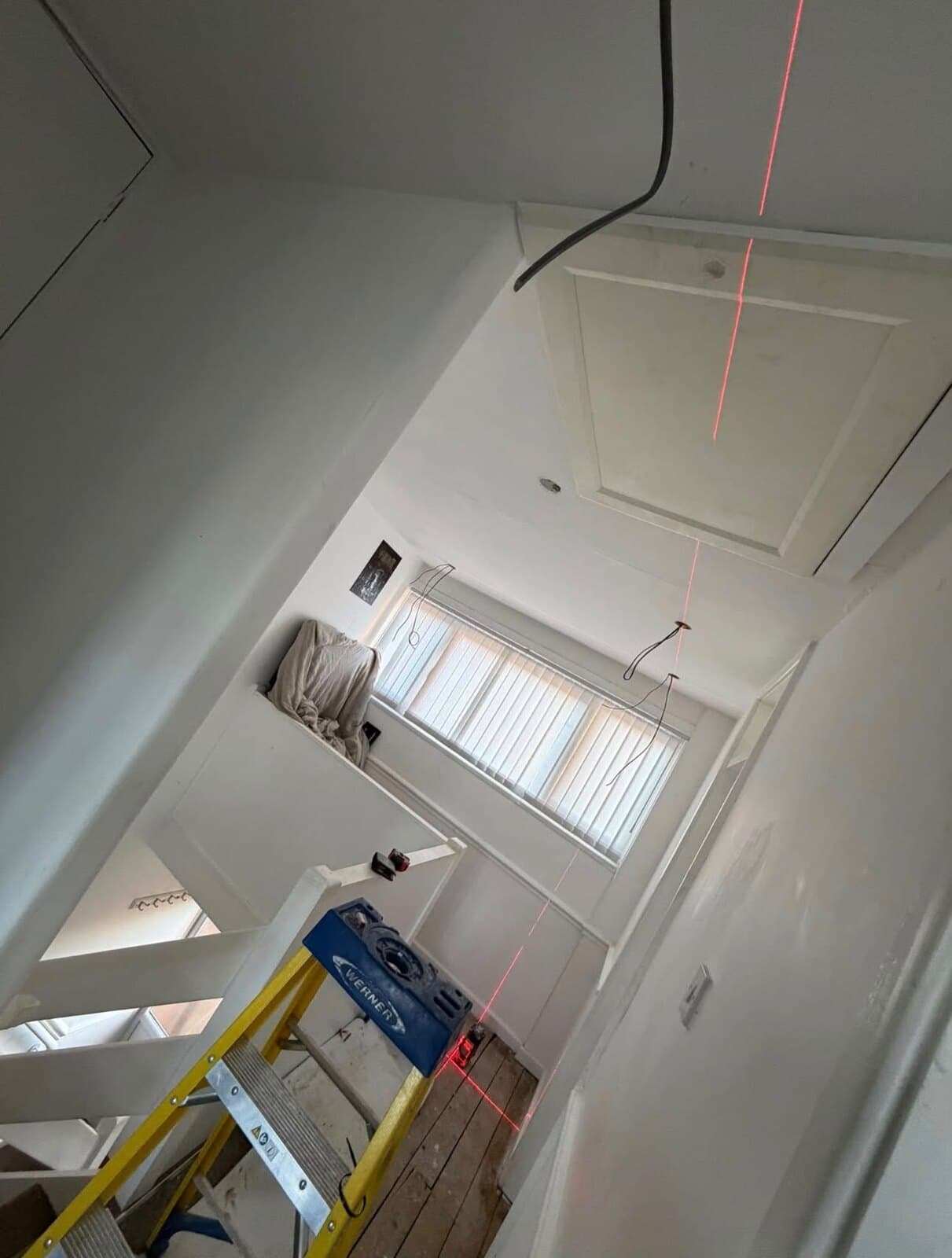 Landing and stairs marked out for new downlights with a cross-line laser