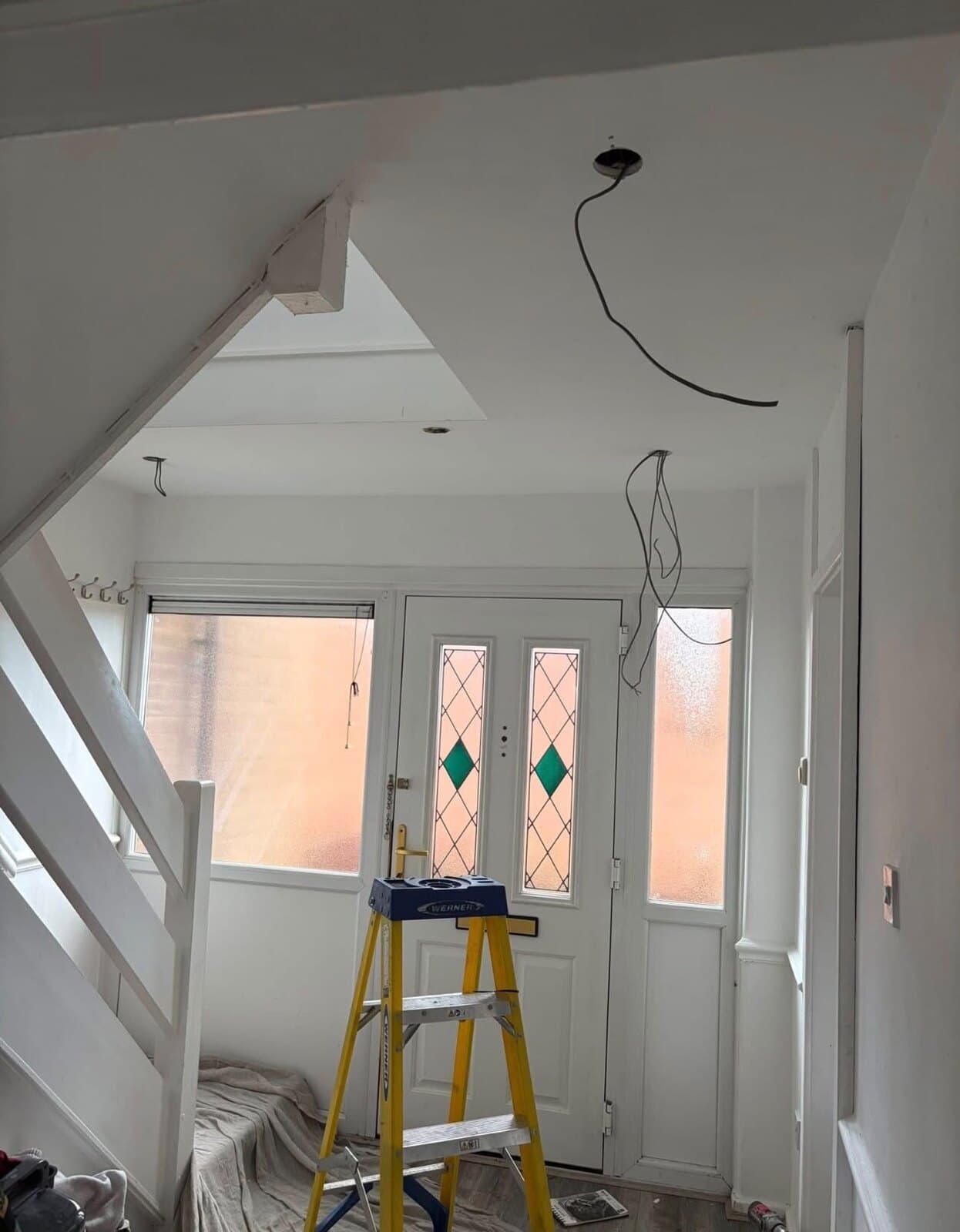 Hallway part way through a rewire, floors sheeted and the old ceiling rose taken down